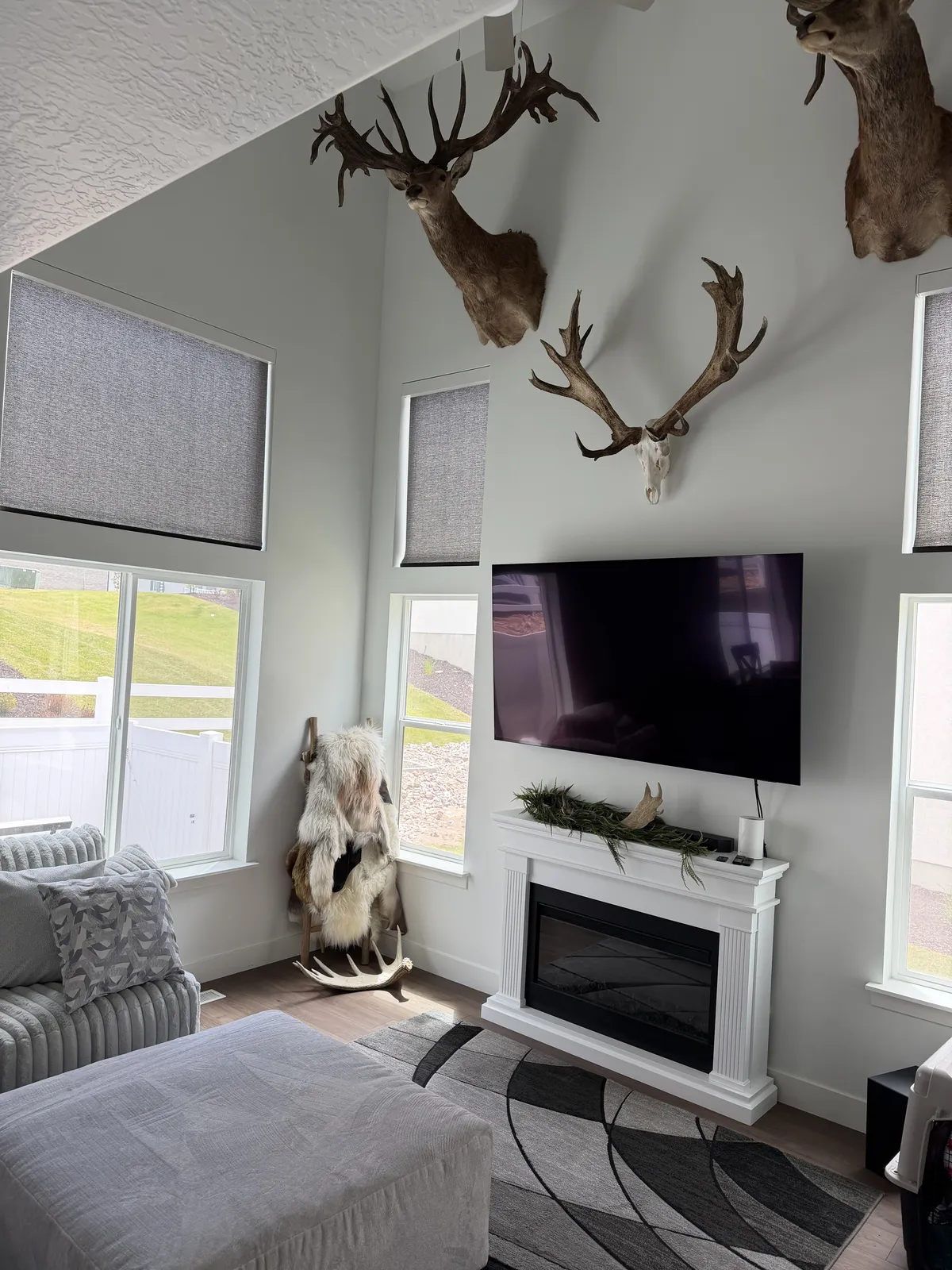 Mountain lodge den with antler decor and two windows in matching light-filtering roller shades