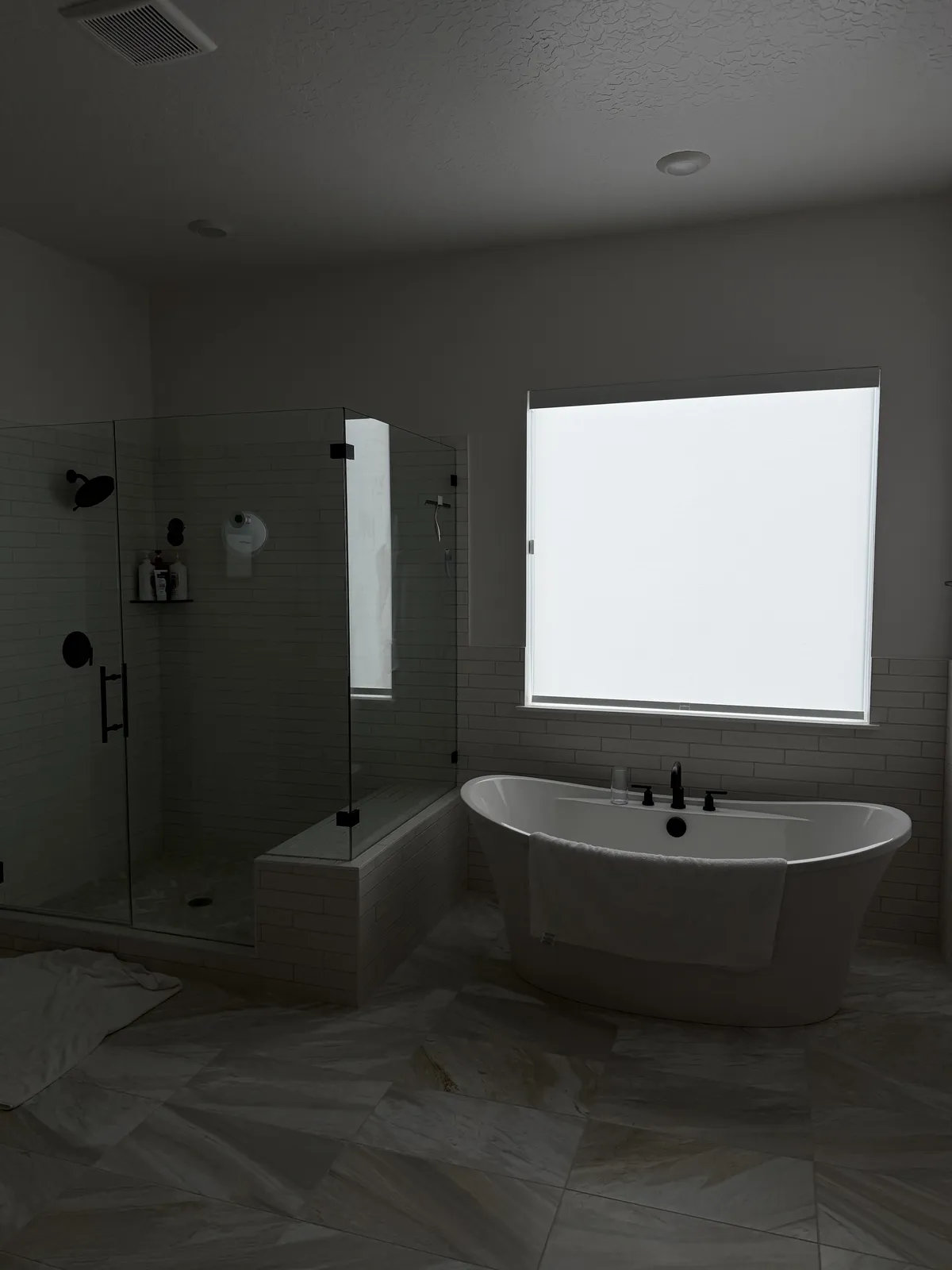 Bright bathroom with a freestanding tub and a light-filtering privacy shade on the window above it